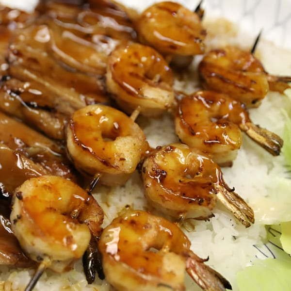 Close-up of Lucky Teriyaki's shrimp and chicken skewers with glossy sauce over white rice.